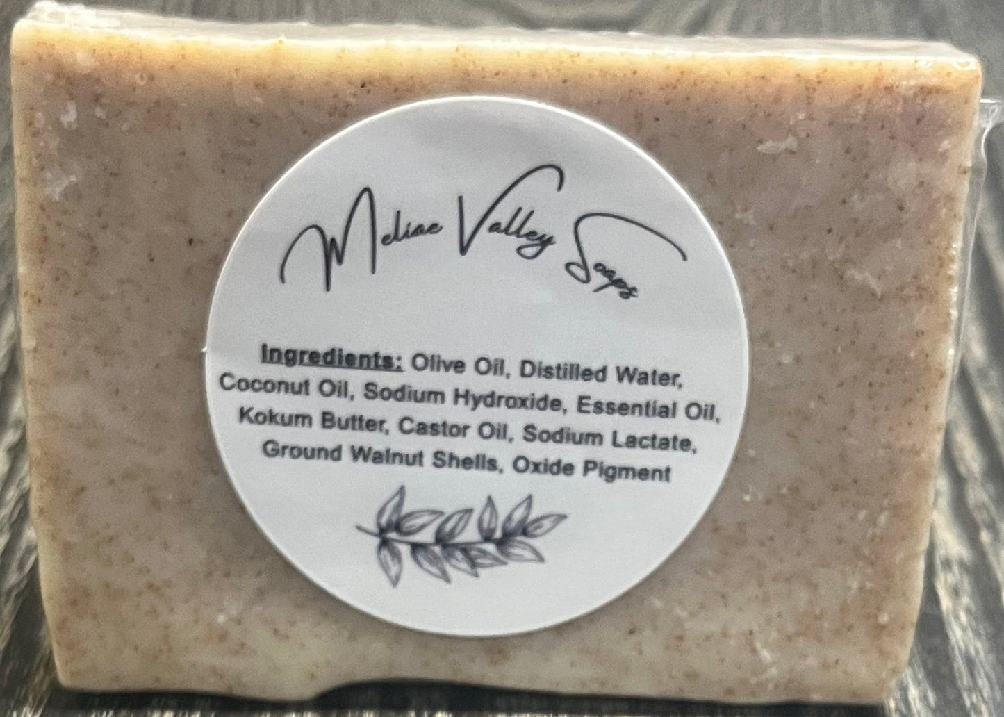 Bar of soap with a label on a wooden surface.