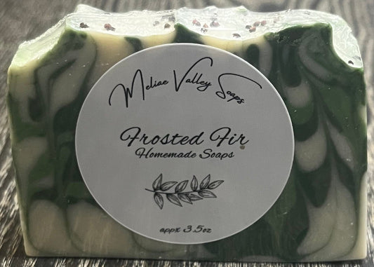 Green and white marbled soap with a white label on a wooden surface.