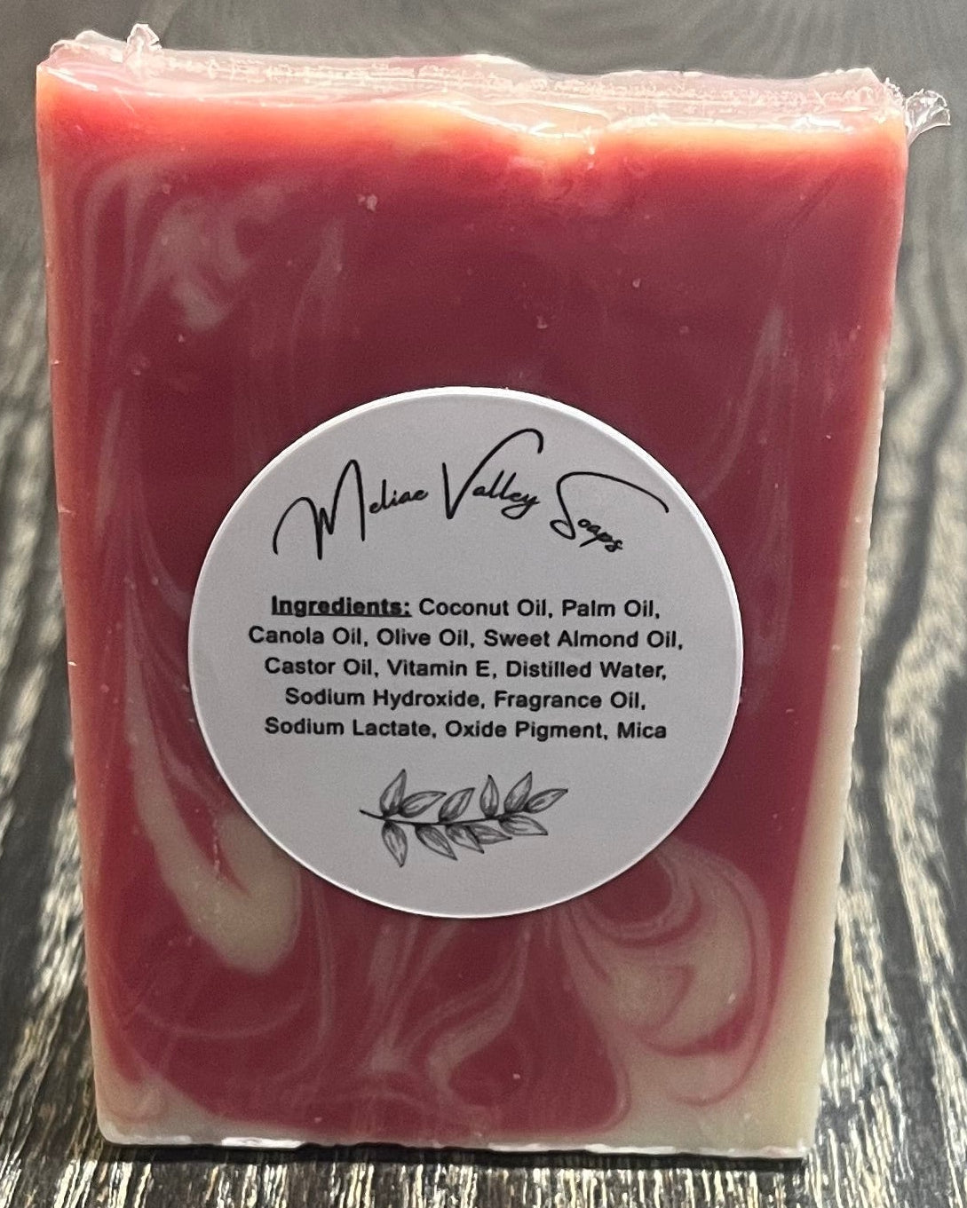 Red soap bar with a label on a wooden surface.