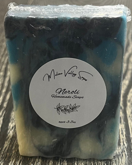 Bar of soap with navy blue, blue, and white swirl design with a white label on a wooden surface.