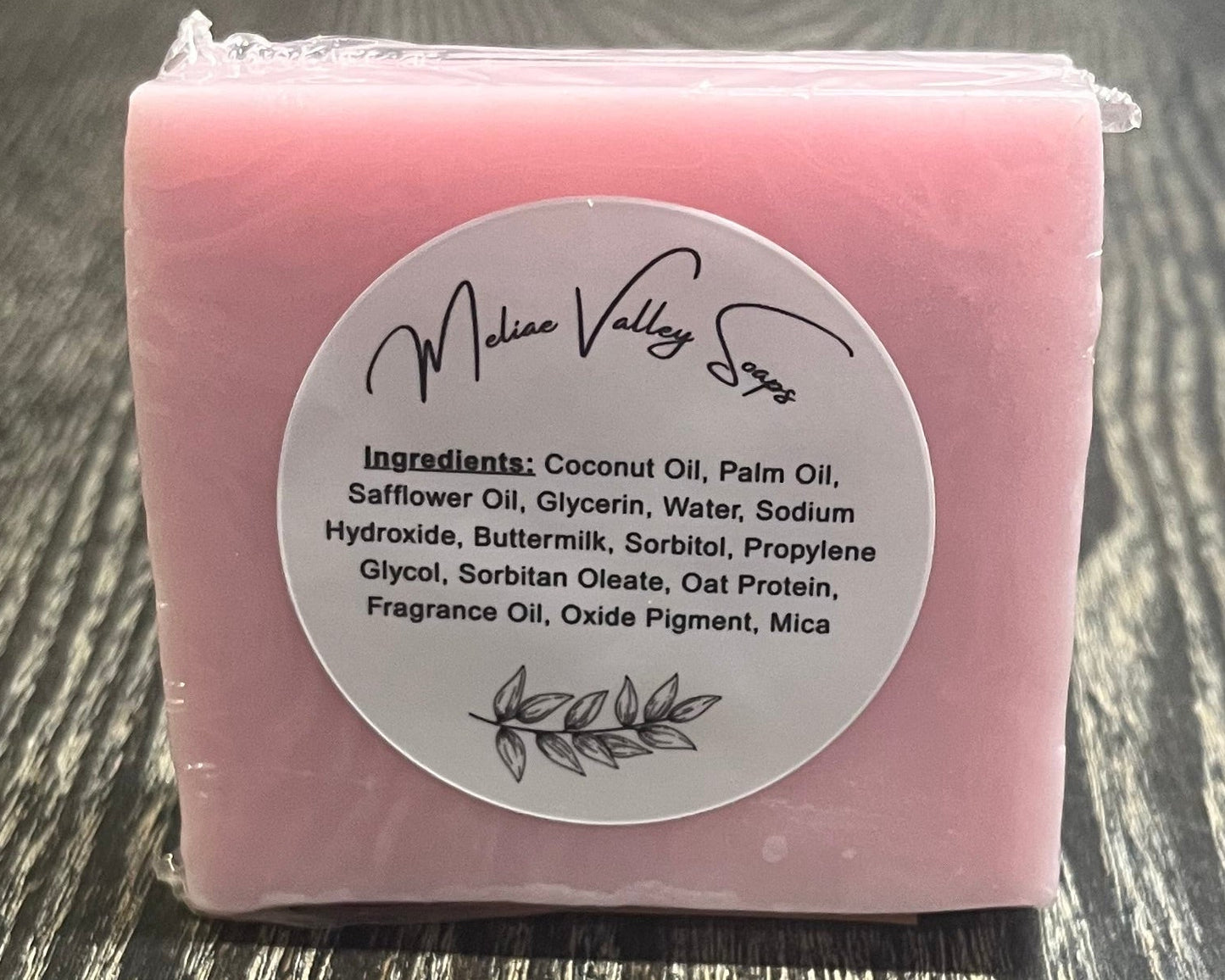 Pink soap bar with a label on a wooden surface.