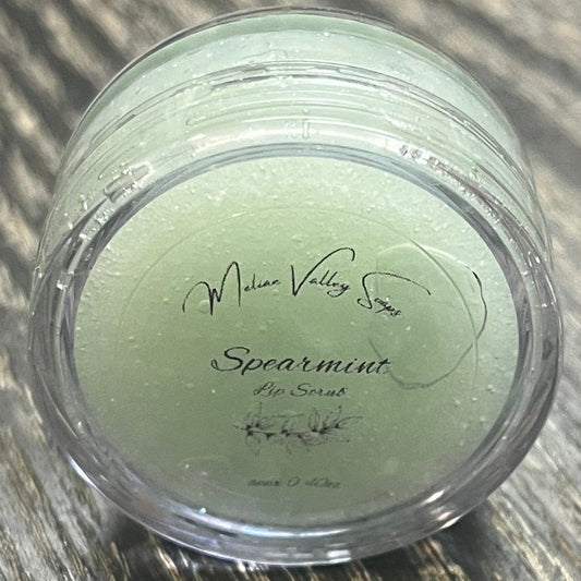 A lip pot filled with sugar dyed mint green. The lip pot is positioned on its side with its label facing the camera.
