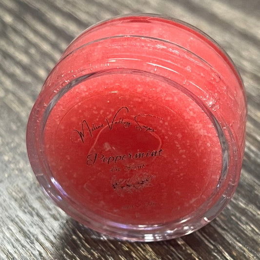 A lip pot filled with sugar dyed red. The lip pot is positioned on its side with its label facing the camera.