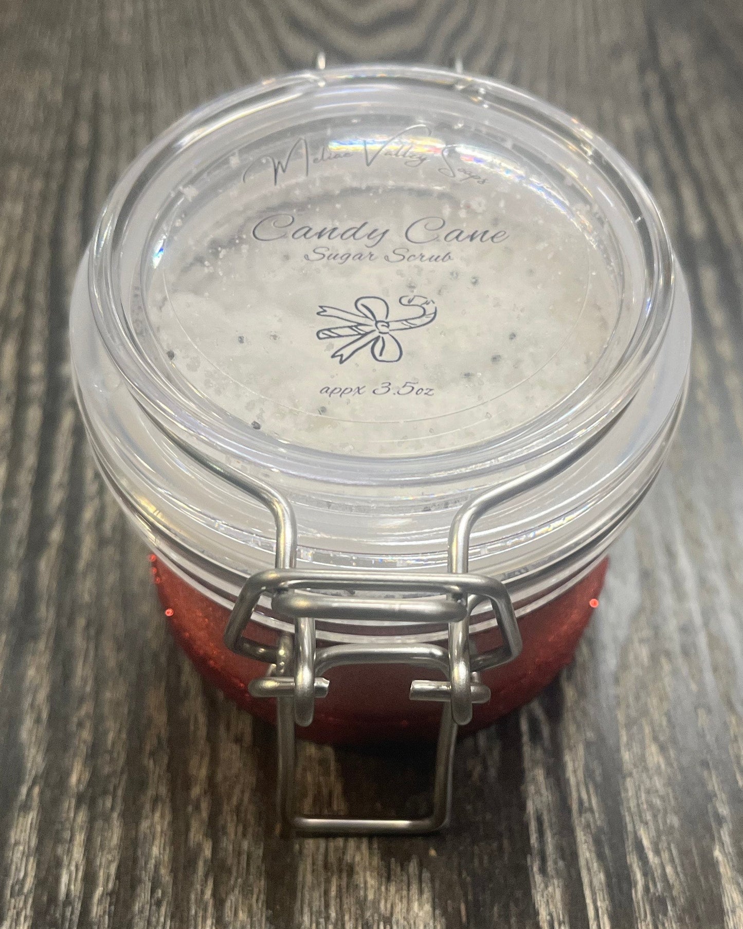 Clear round jar with a sticker on top. You see through the jar to white sugar.