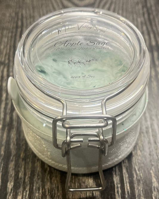 Clear round jar with a sticker on top. You see through to the jar to green body butter.