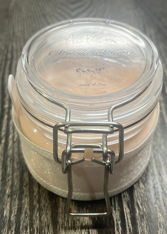 Clear round jar with a sticker on top. You see through to the jar to bronze body butter.