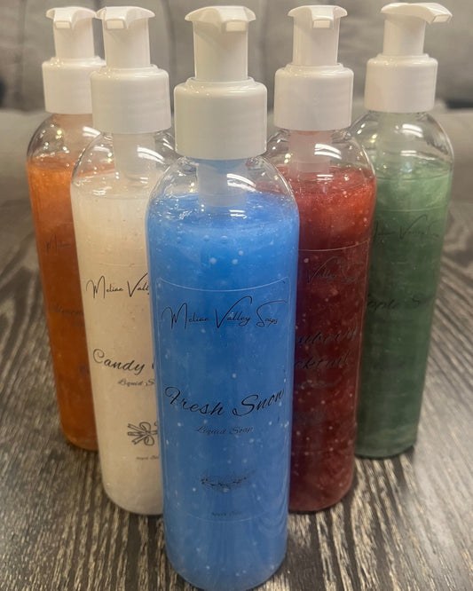 A set of pump bottles with different colored liquids, bronze, white, blue, red, and green, in a 'V' shape on a wooden surface.
