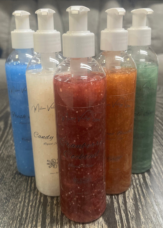 A set of pump bottles with different colored liquids, bronze, white, blue, red, and green, in a 'V' shape on a wooden surface.