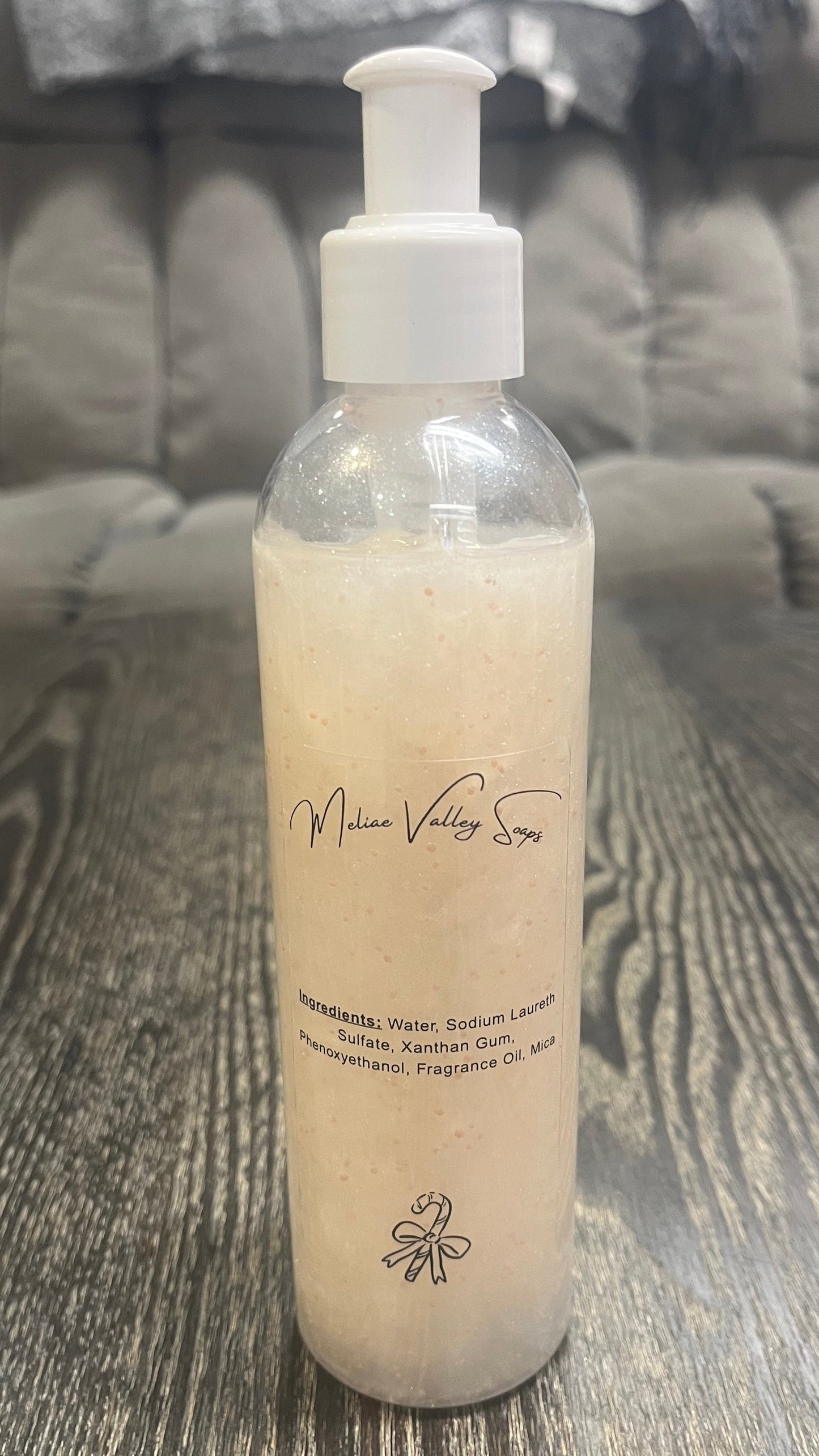 A clear pump bottle with a white nozzle full of red liquid with white beads on a textured surface.