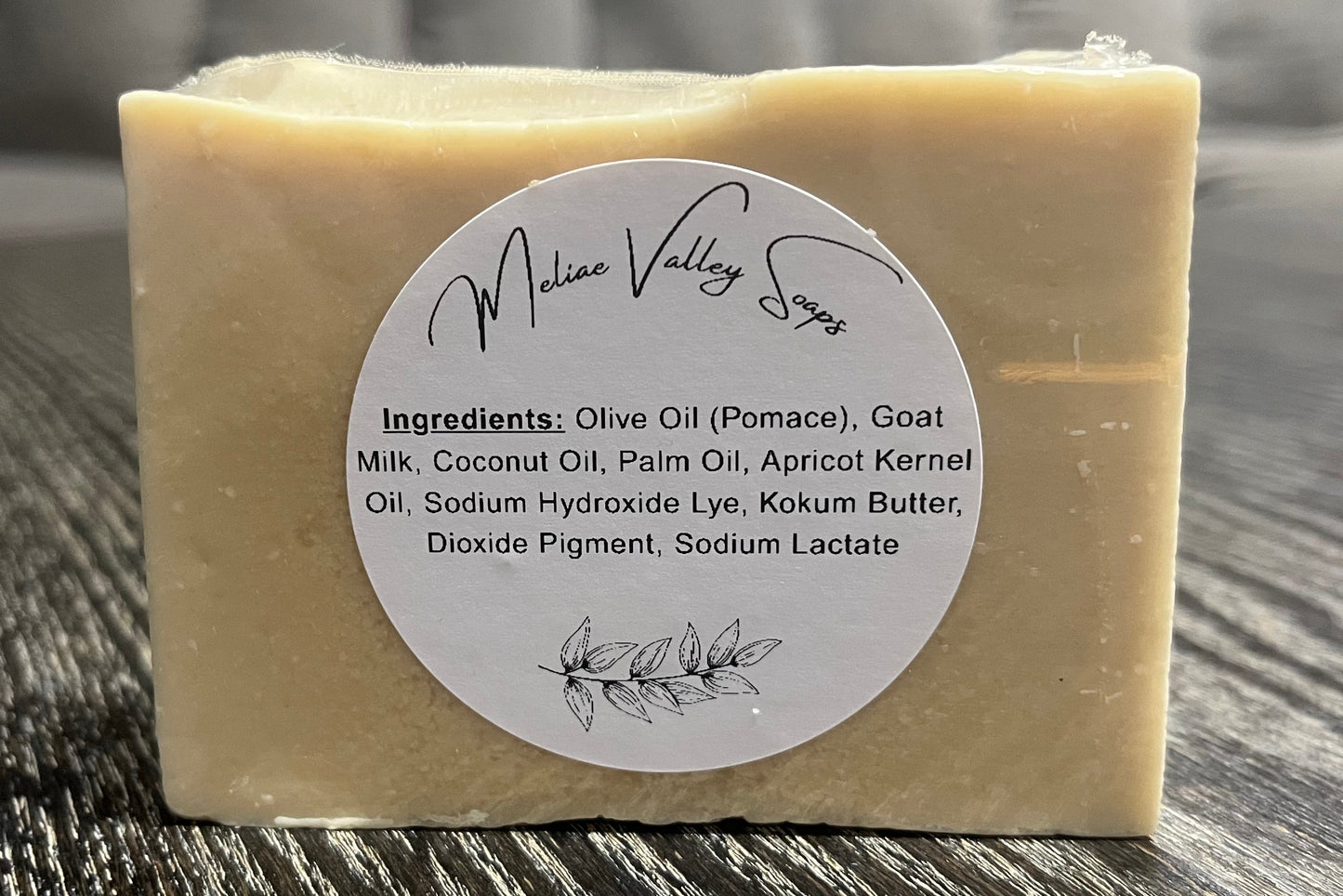 A beige bar of soap with a white ingredients label on a textured surface.