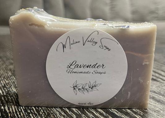 Bar of lavender soap with a label on a wooden surface.