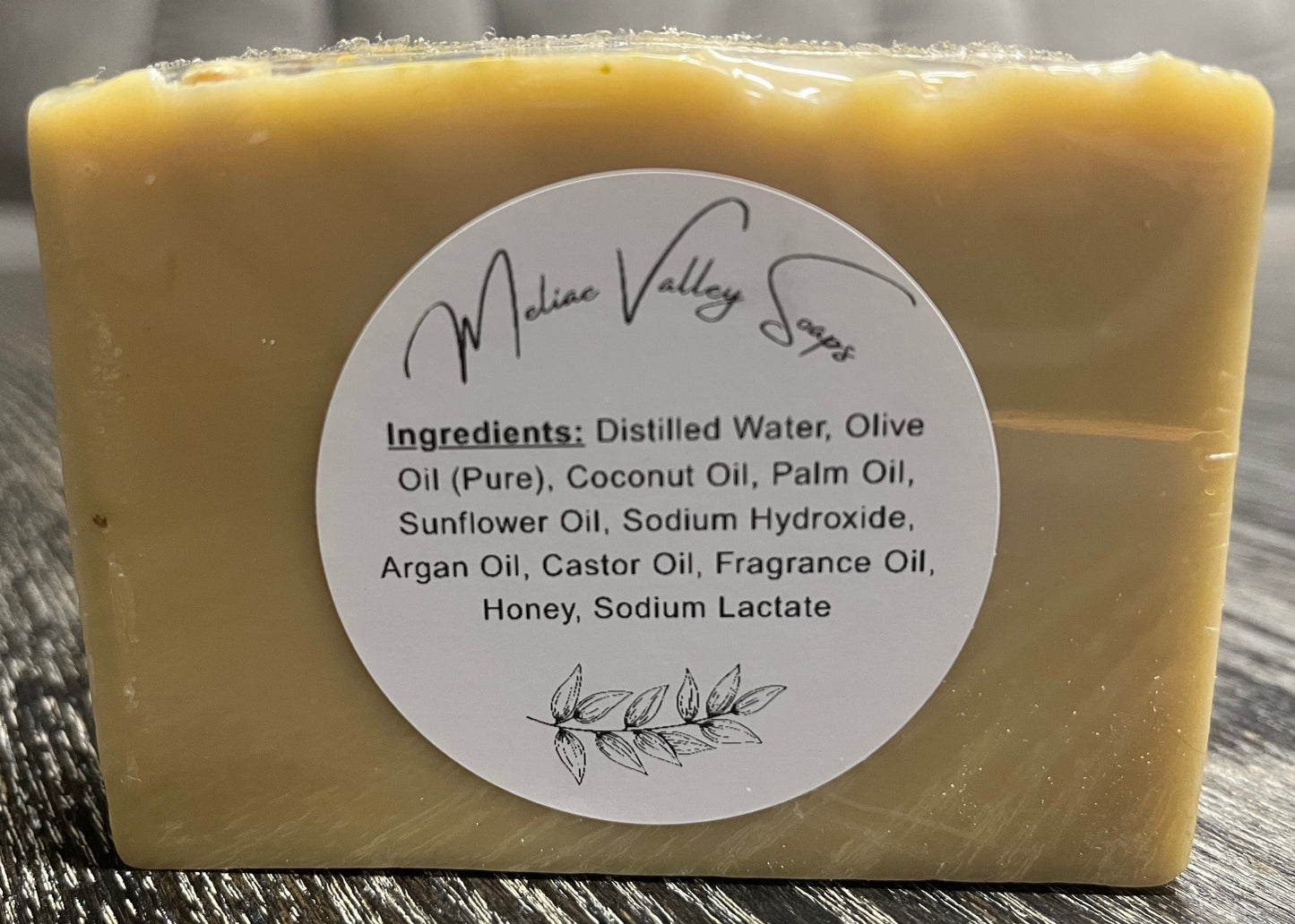 Bar of soap with a white ingredients label on a wooden surface.