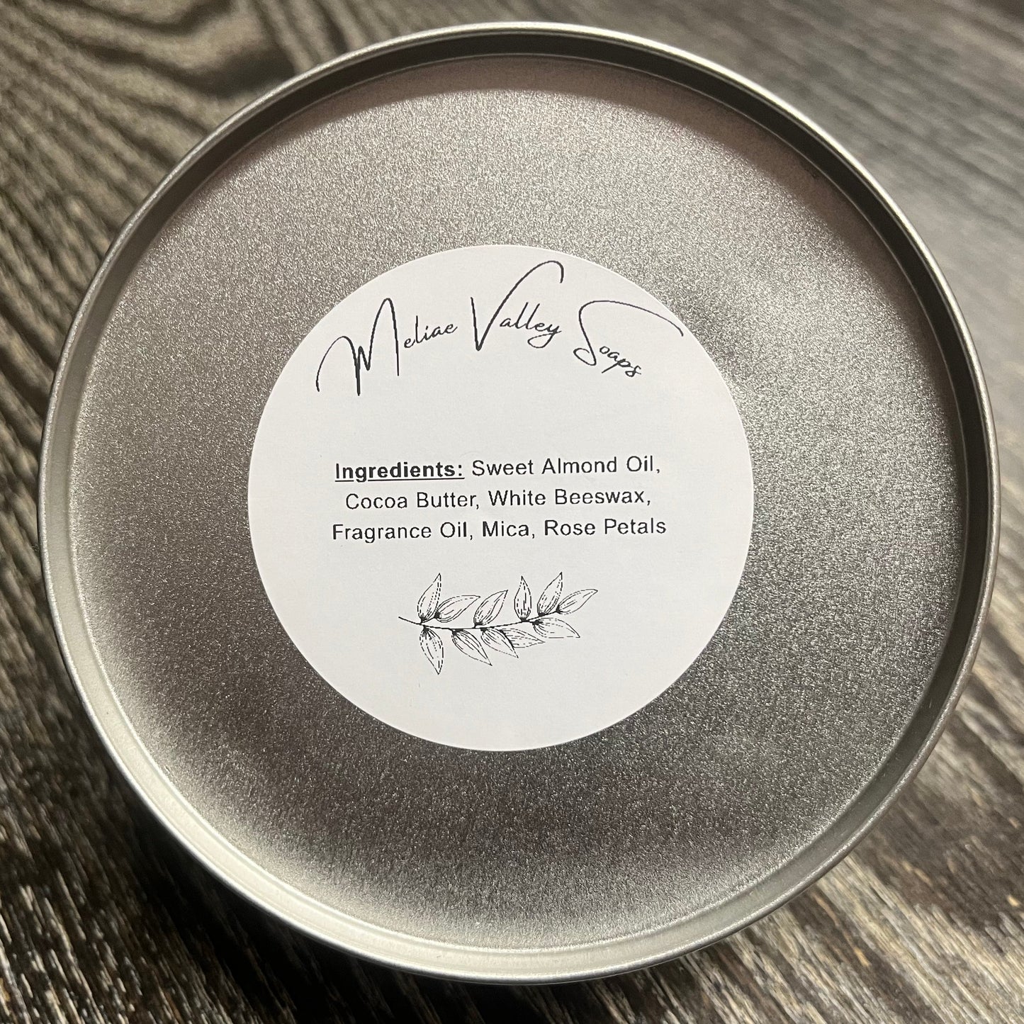 Silver tin with a white ingredients label on a wooden surface.