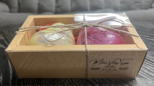 A soap and a lotion bar in a decorative box with a clear sticker and twine.