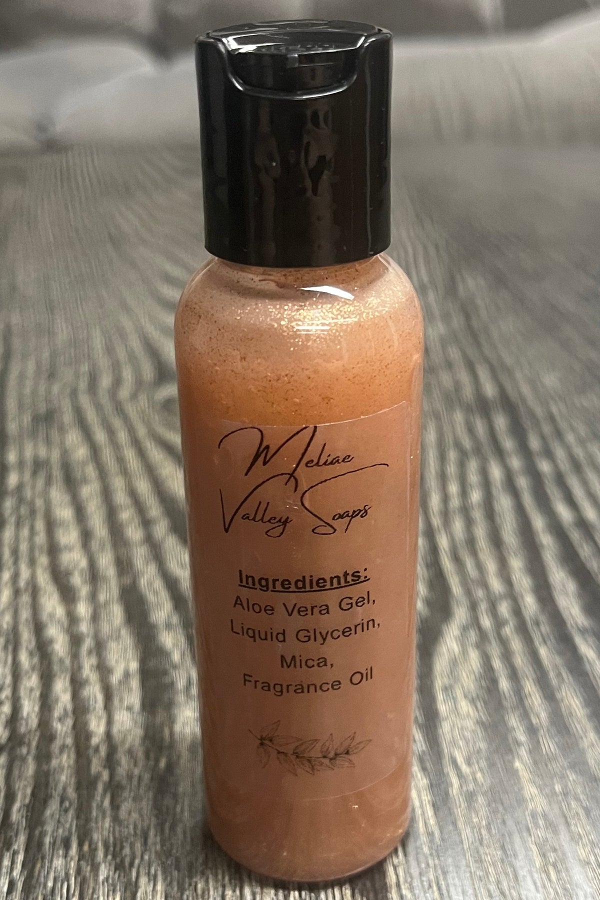 A small bottle of bronze body shimmer with a clear ingredients label.
