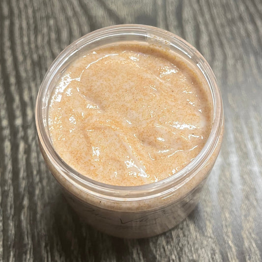 Jar of light brown walnut body scrub. You can slightly see a clear label on the front from this angle.