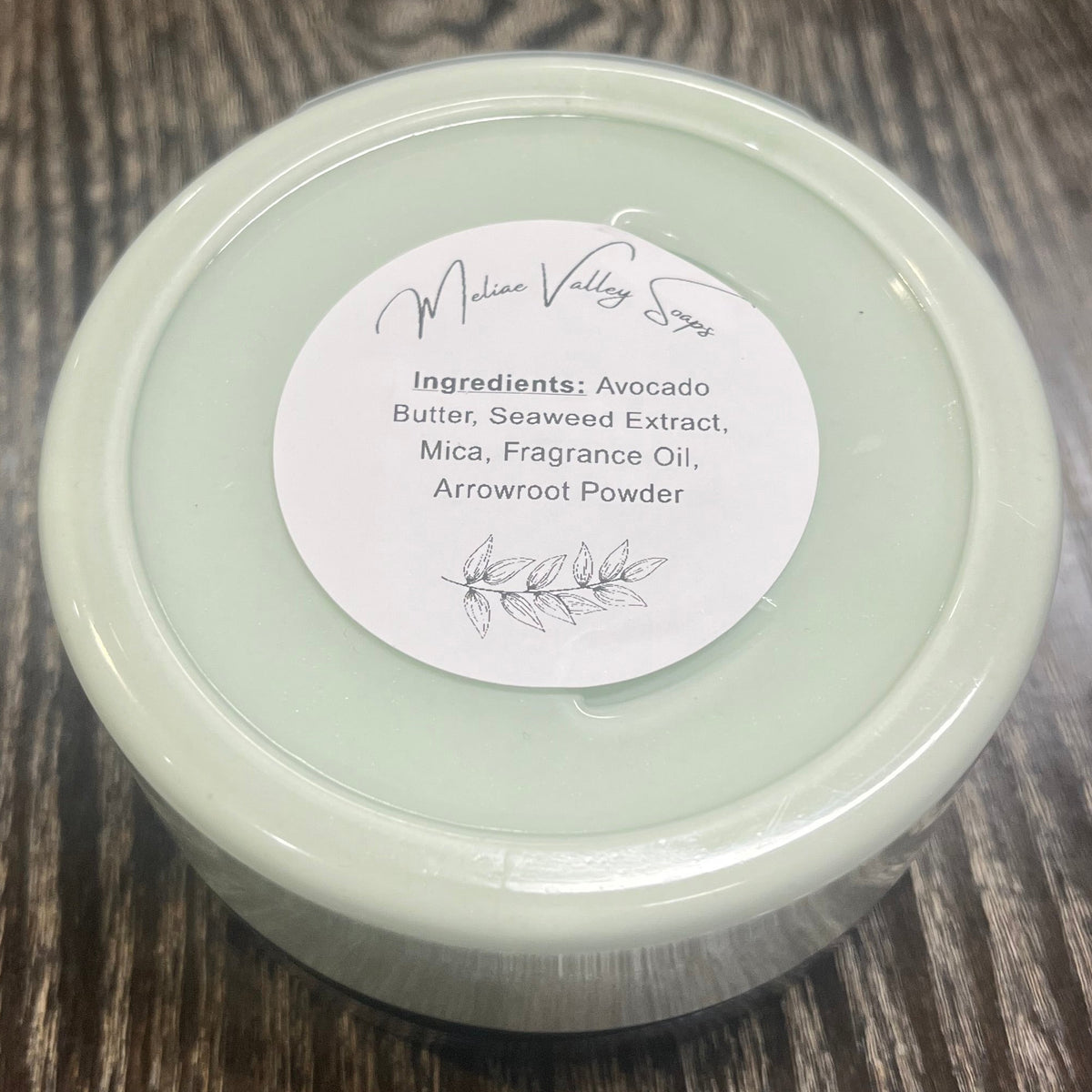 Jar of green whipped body butter with a white ingredients label.
