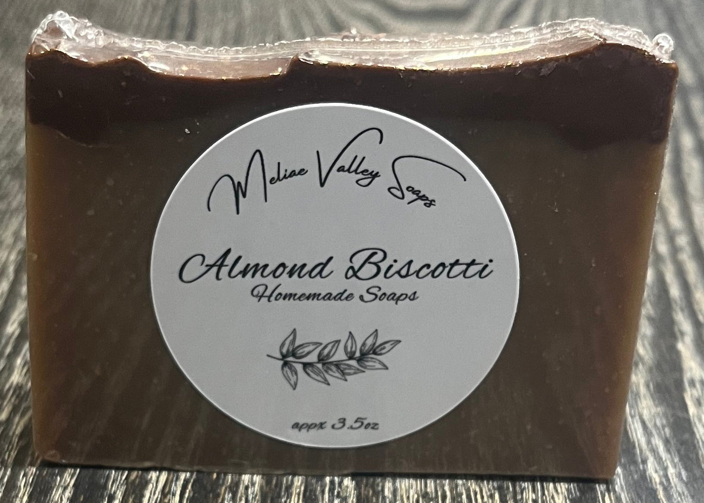 A tan soap bar with a darker brown top layer, with a white label on the front. 