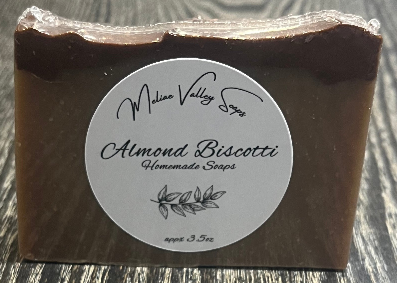 A tan soap bar with a darker brown top layer, with a white label on the front. 