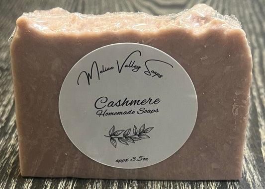 A light purple bar of soap with a white label on a dark wooden surface. 