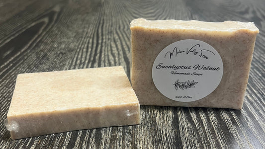 Two soap bars on a wooden surface with a label on one of them.