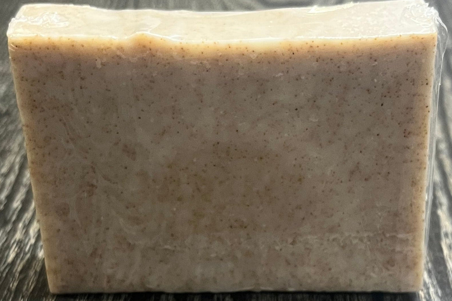 A beige soap bar with darker brown specs of ground walnut shells. 