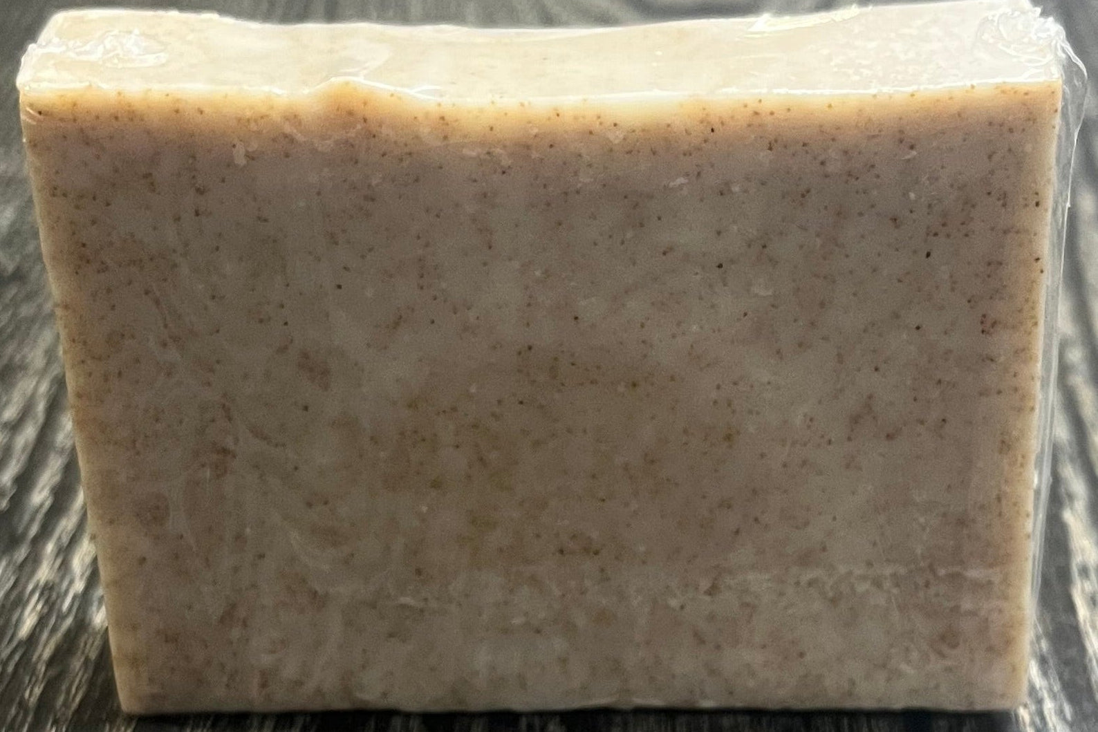 A beige soap bar with darker brown specs of ground walnut shells. 