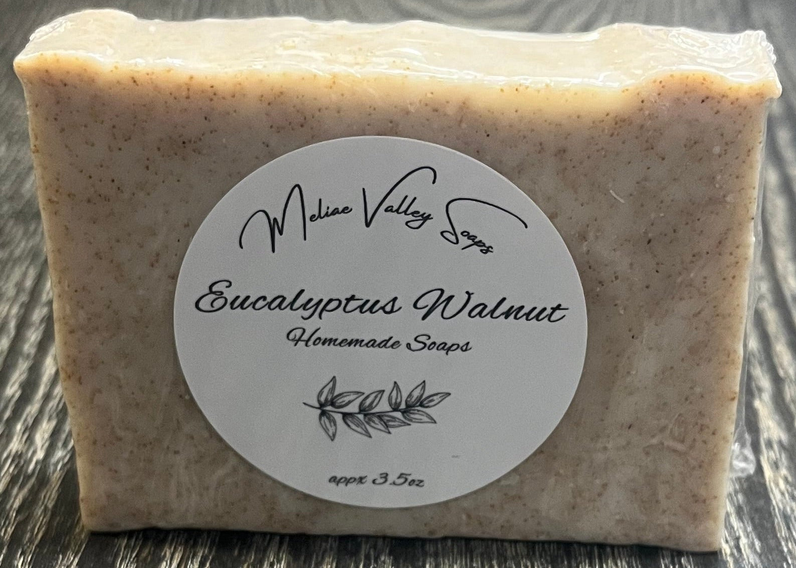 Bar of soap with a label on a wooden surface.