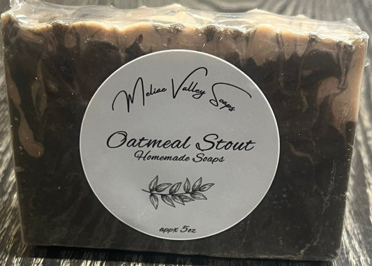 A black and beige marble-patterned soap with a white label on a wooden surface. 