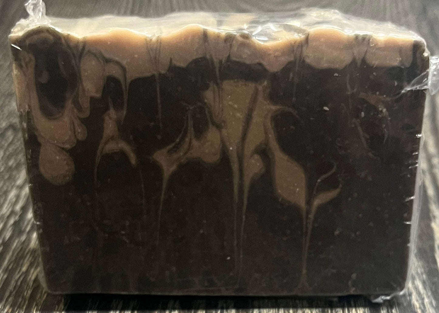 A black and beige marble-patterned soap on a wooden surface. 