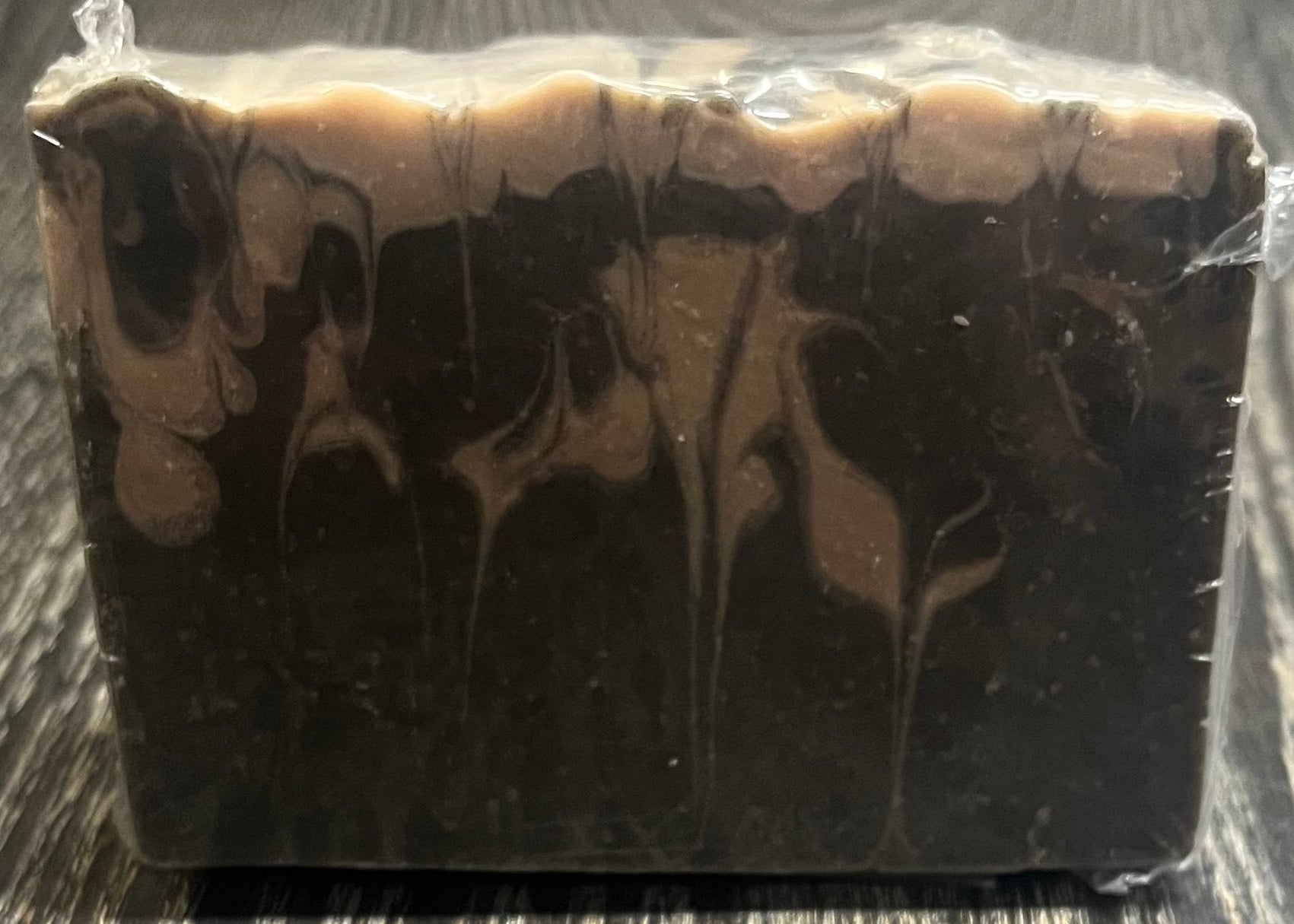 A black and beige marble-patterned soap on a wooden surface. 