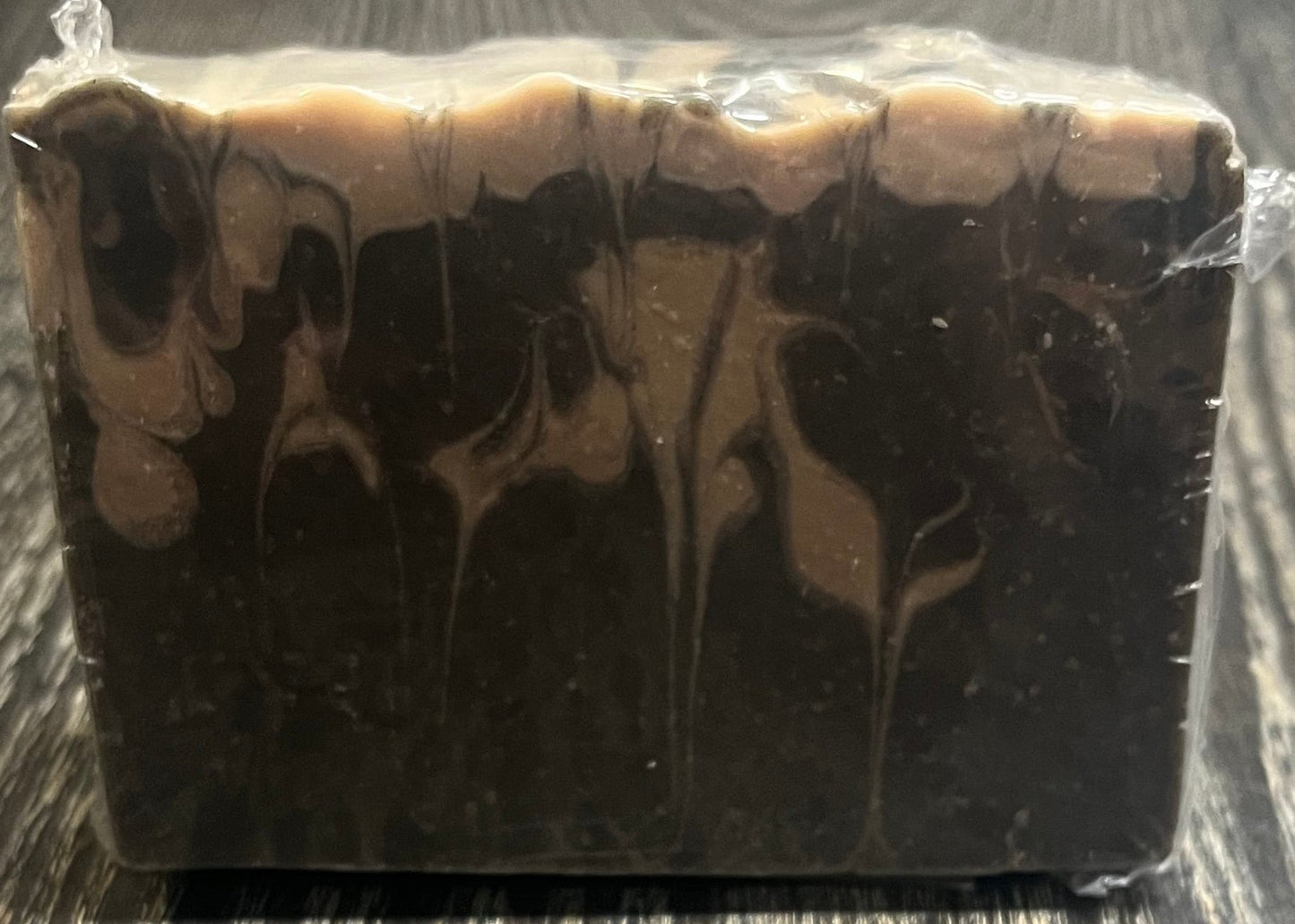 A black and beige marble-patterned soap on a wooden surface. 