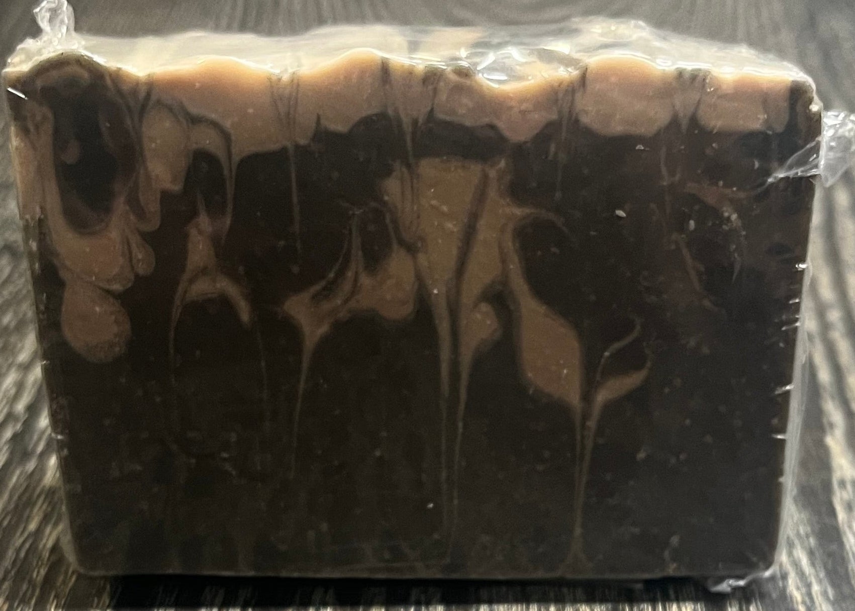A black and beige marble-patterned soap on a wooden surface. 