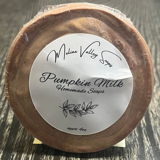 Round brown soap bar with a white label on a wooden surface. 