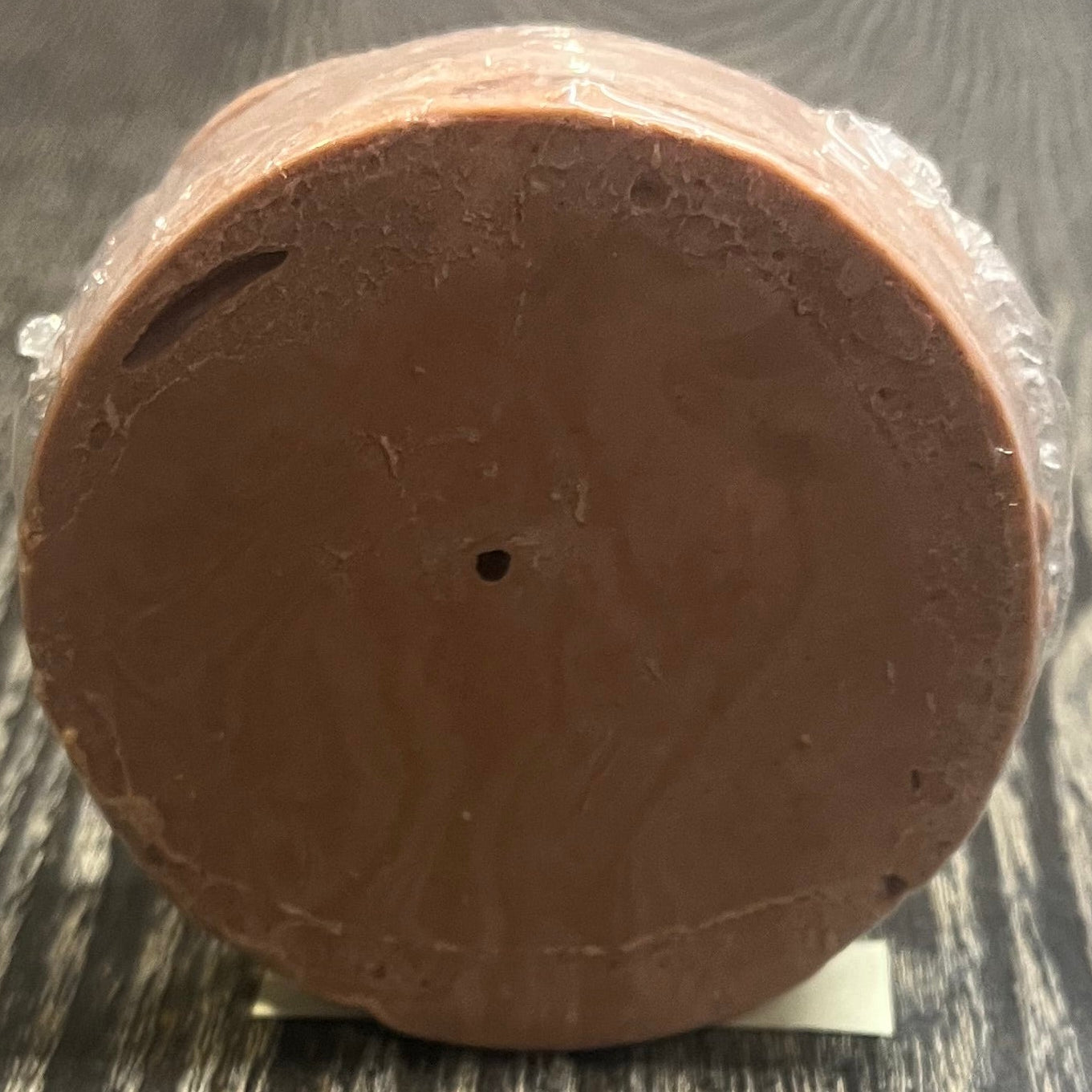 Round brown soap bar on a wooden surface. 