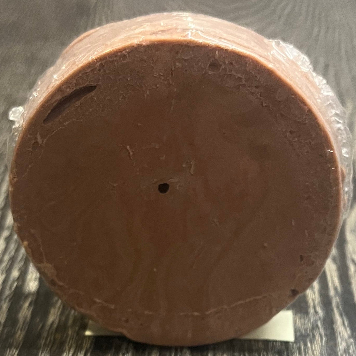Round brown soap bar on a wooden surface. 