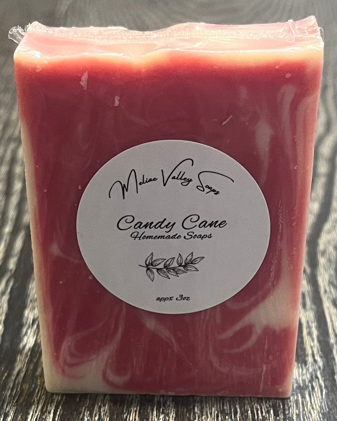 Red bar of soap with a label on a wooden surface.