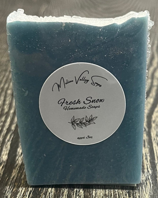 A tall blue bar of soap with a heavy sprinkle of glitter on top faces the camera, showing a white label. 