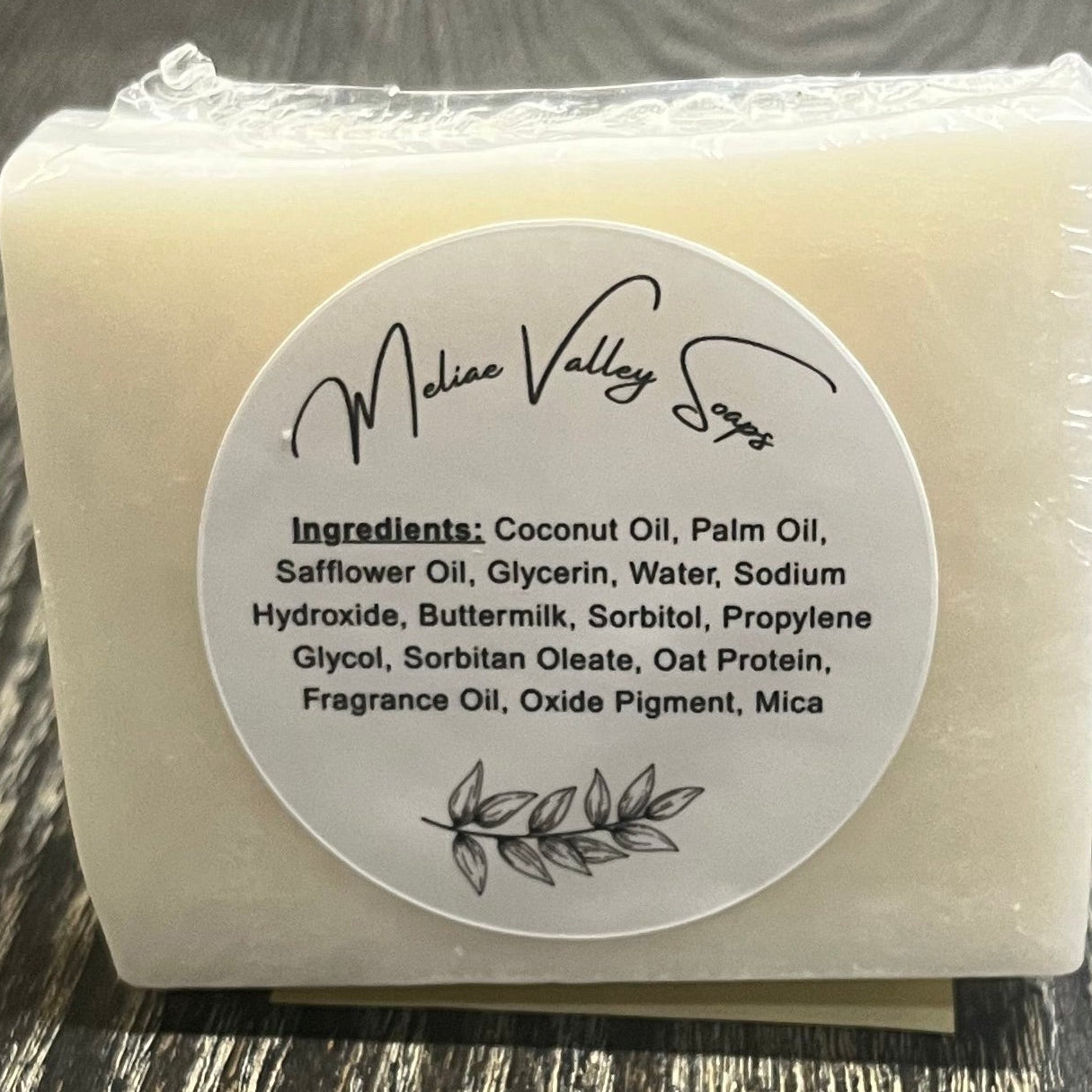 A white bar of soap with a label on a wooden surface.