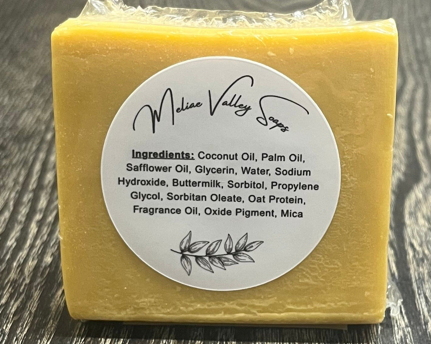 Yellow bar of soap with a label on a wooden surface.