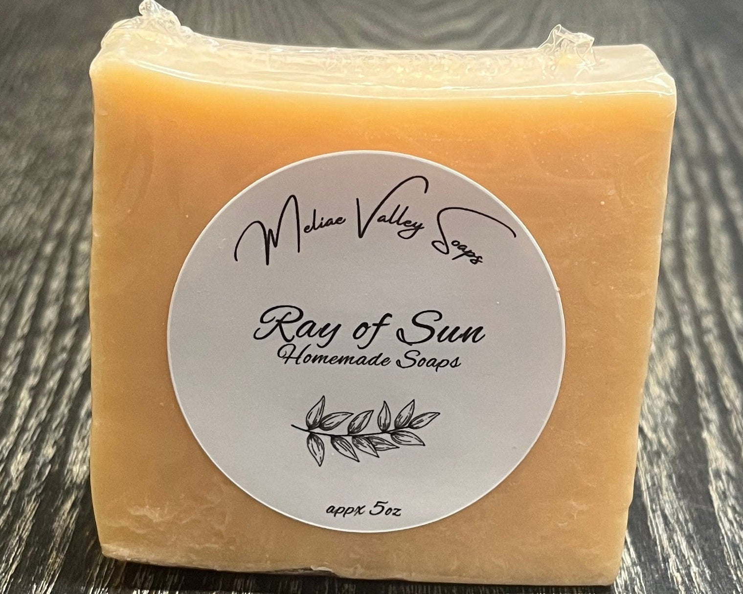 An orange bar of soap with a label on a wooden surface.