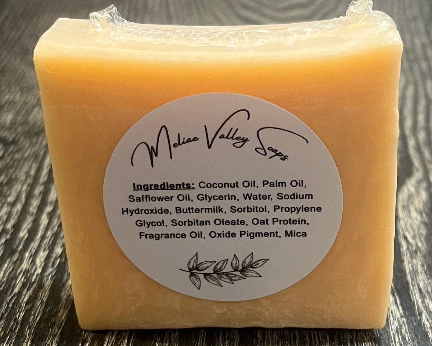 An orange bar of soap with a label on a wooden surface.