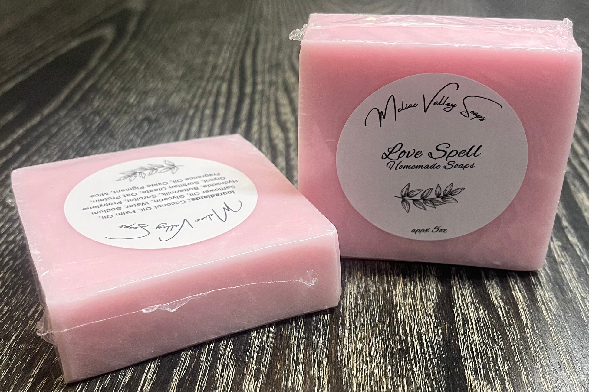 Pink soap bar with a label on a wooden surface.