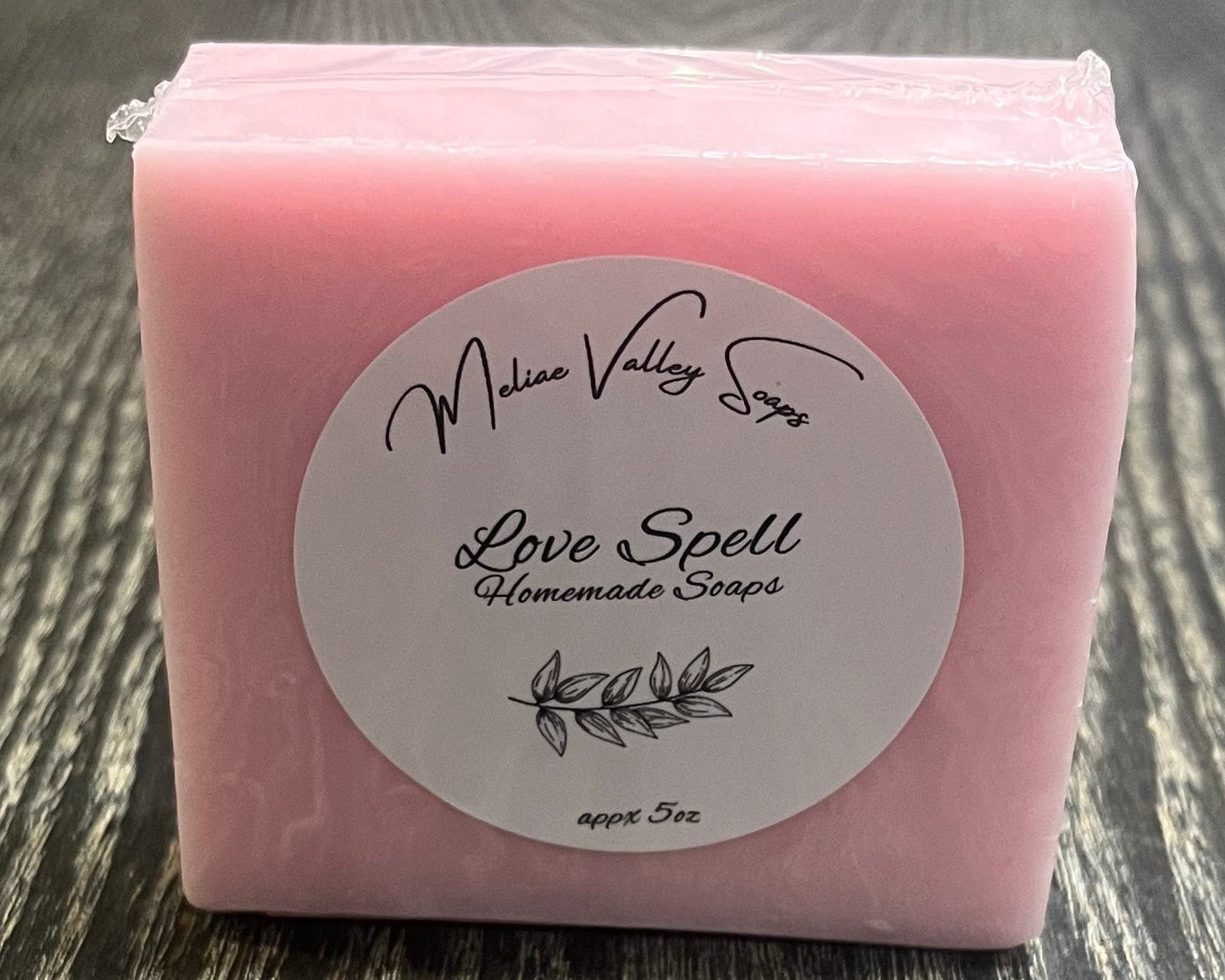 Pink soap bar with a label on a wooden surface.
