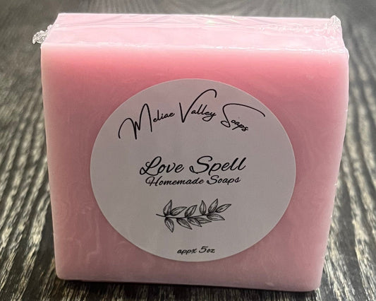 Pink soap bar with a label on a wooden surface.