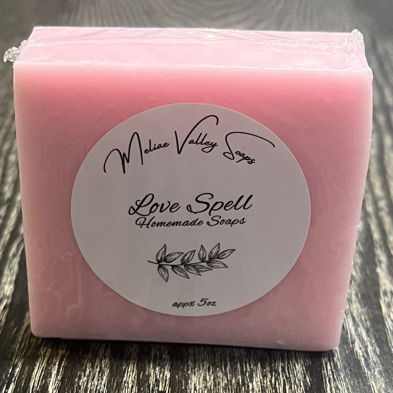 Pink soap bar with a label on a wooden surface.