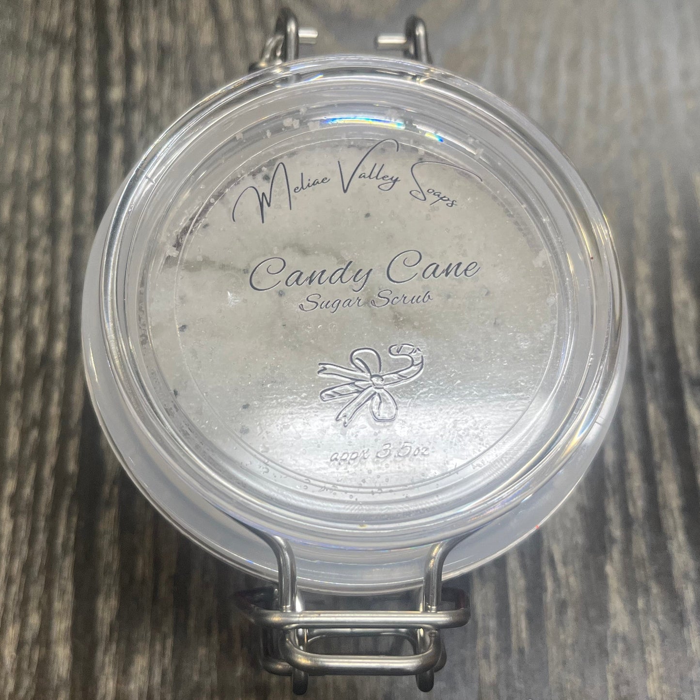 Clear round jar with a sticker on top. You see through the jar to white sugar. 