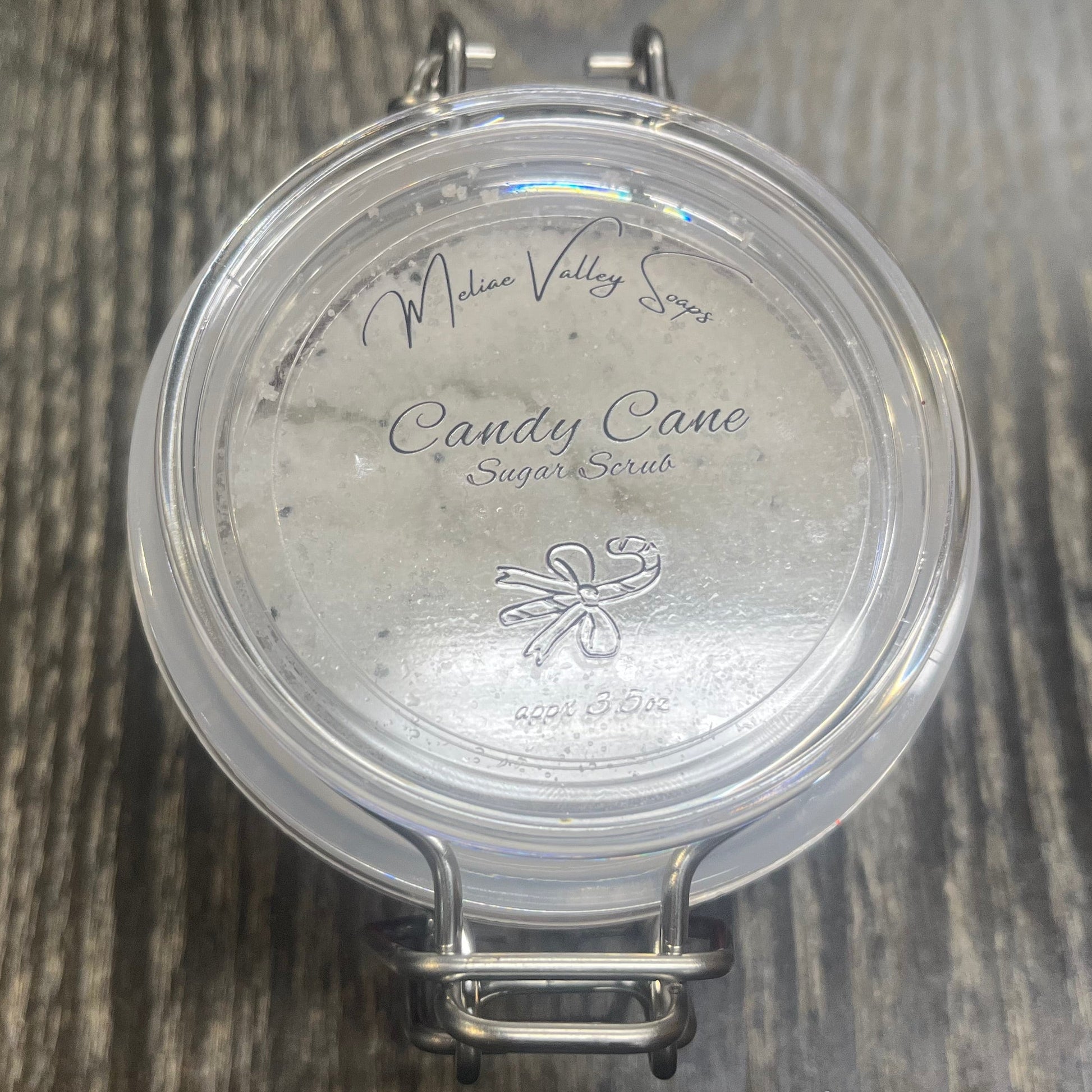 Clear round jar with a sticker on top. You see through the jar to white sugar. 