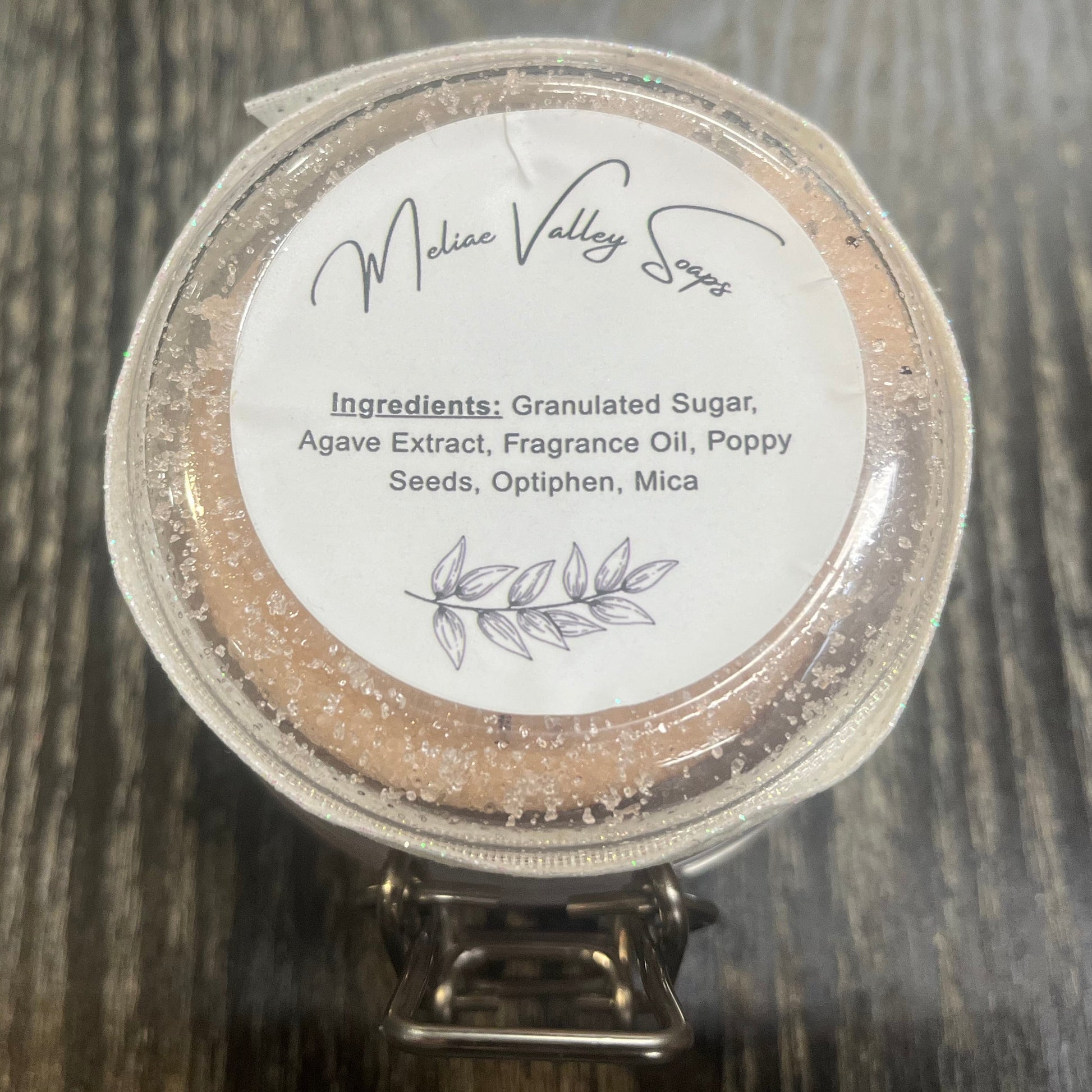 The bottom of a jar with a white ribbon around it. The bottom of the jar has a white sticker with the ingredients on it. 