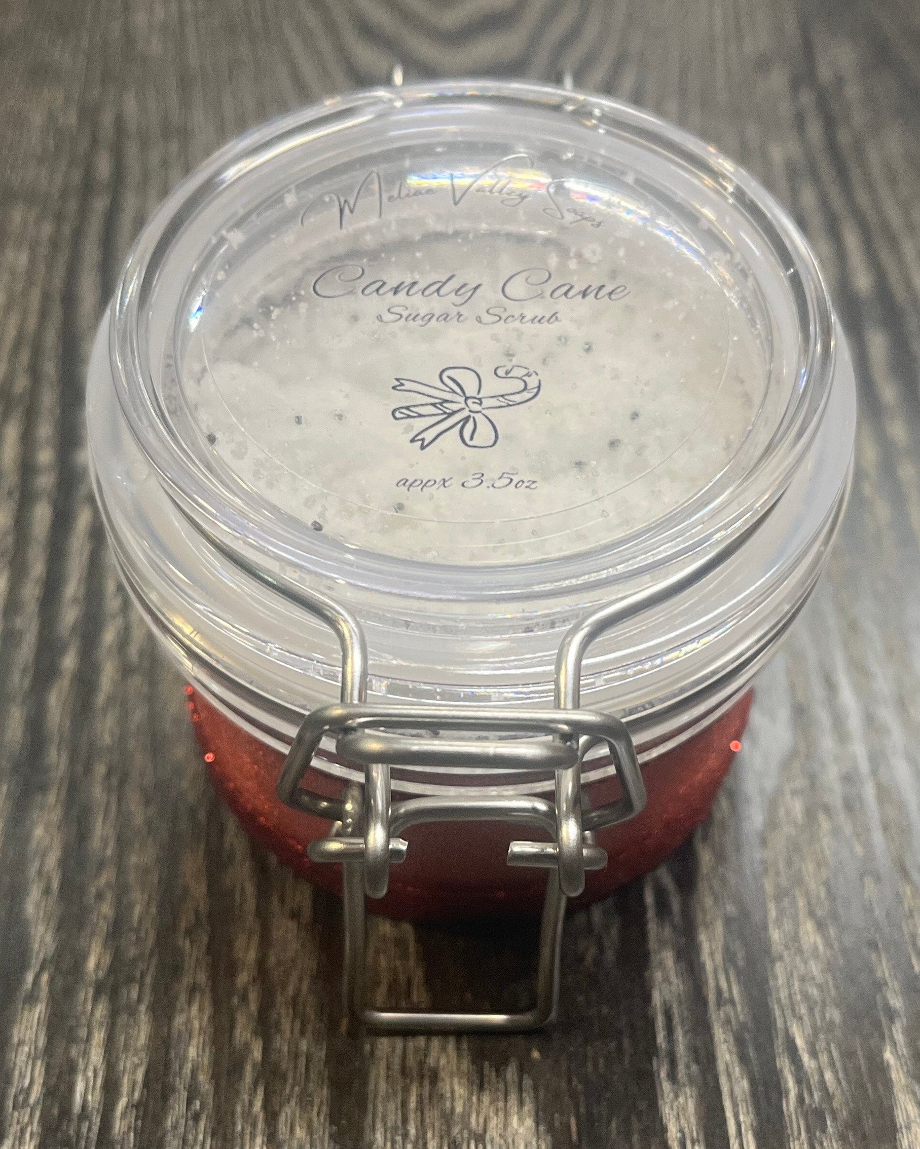 Clear round jar with a sticker on top. You see through the jar to white sugar. 